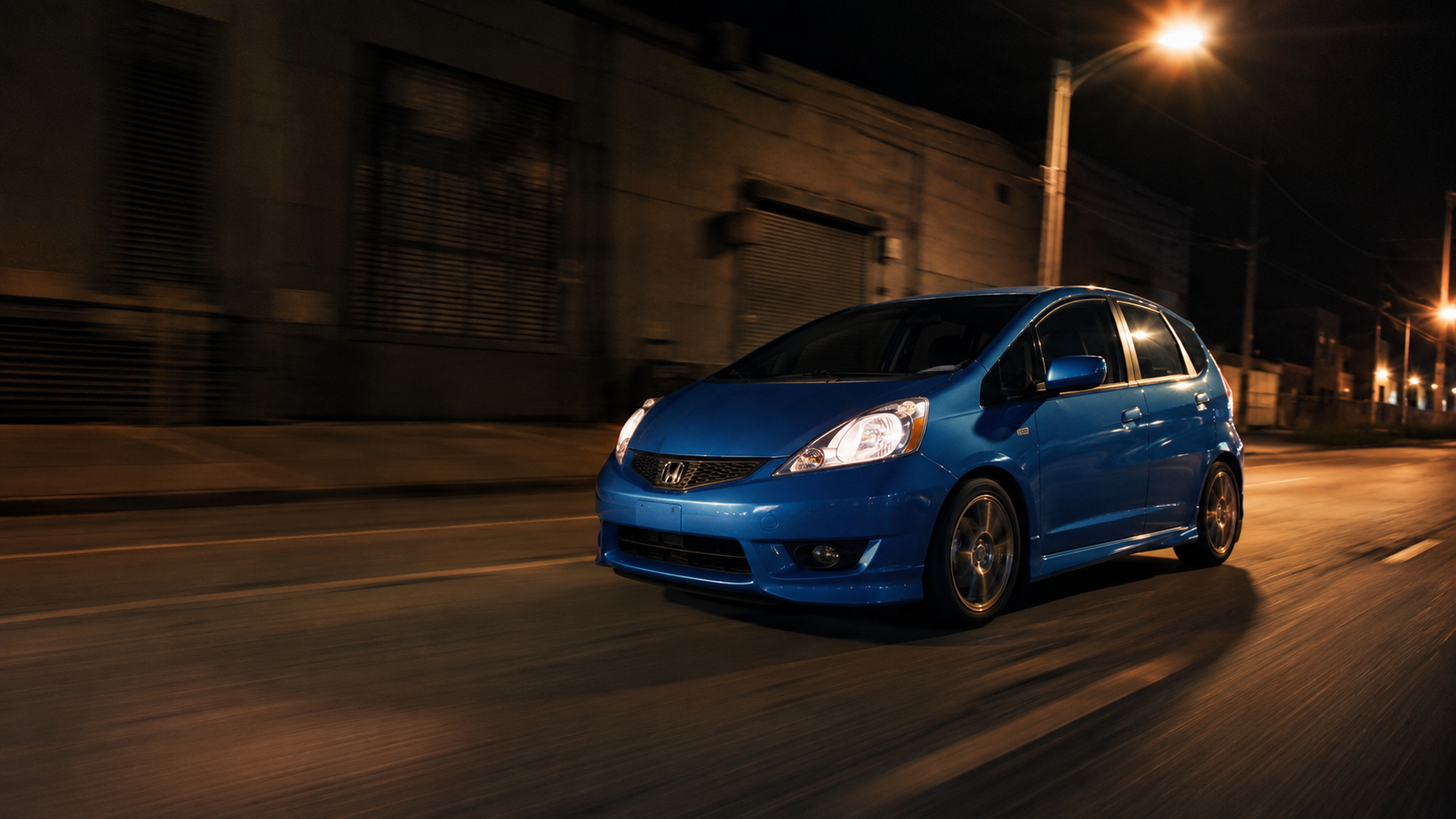 Blue Honda Fit driving at night